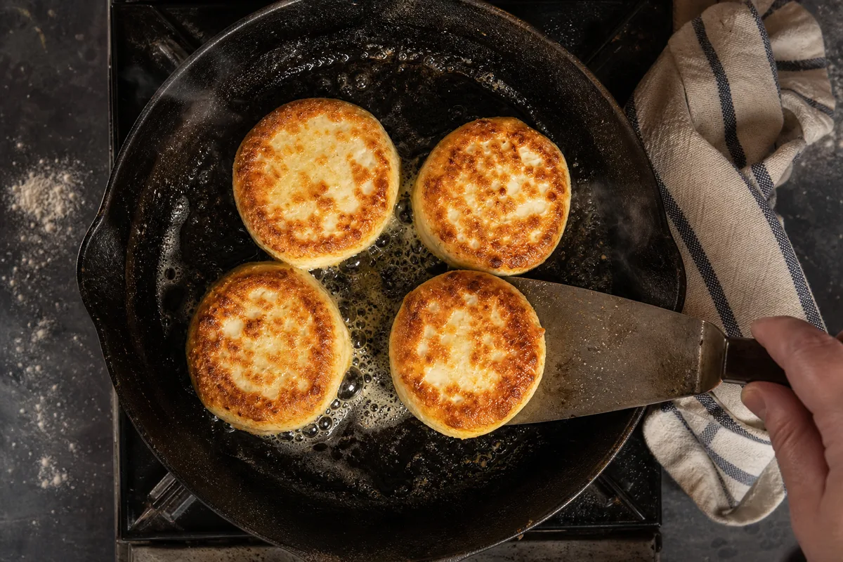 Palets de pâte au fromage blanc dorant dans une poêle en fonte, vue de dessus